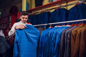 A beared man looking at the blue checked suit jacket held in his hand