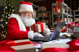 Santa Claus checking his orders on a laptop